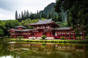 Red Japanese Temple single storey reflected in a lake, mountain background